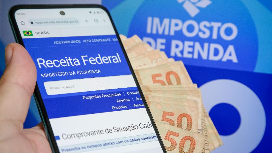 Celular com aplicativo do imposto de renda com notas de dinheiro ao lado