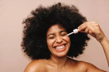 Mulher negra aplicando produtos de beleza no rosto