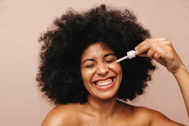 Mulher negra aplicando produtos de beleza no rosto